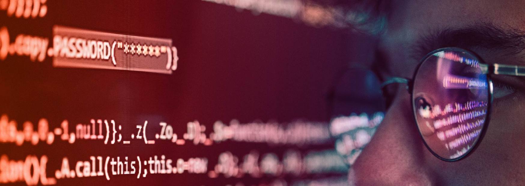 primo piano di uno schermo che mostra la stringa di codice password mascherata da asterischi, con il riflesso di un programmatore sugli occhiali.